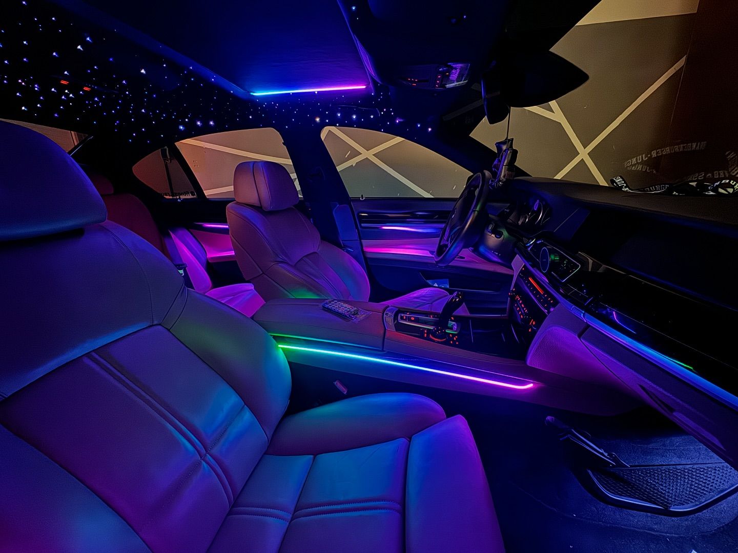Car interior with multicolour ambient lighting and a starlight headliner
