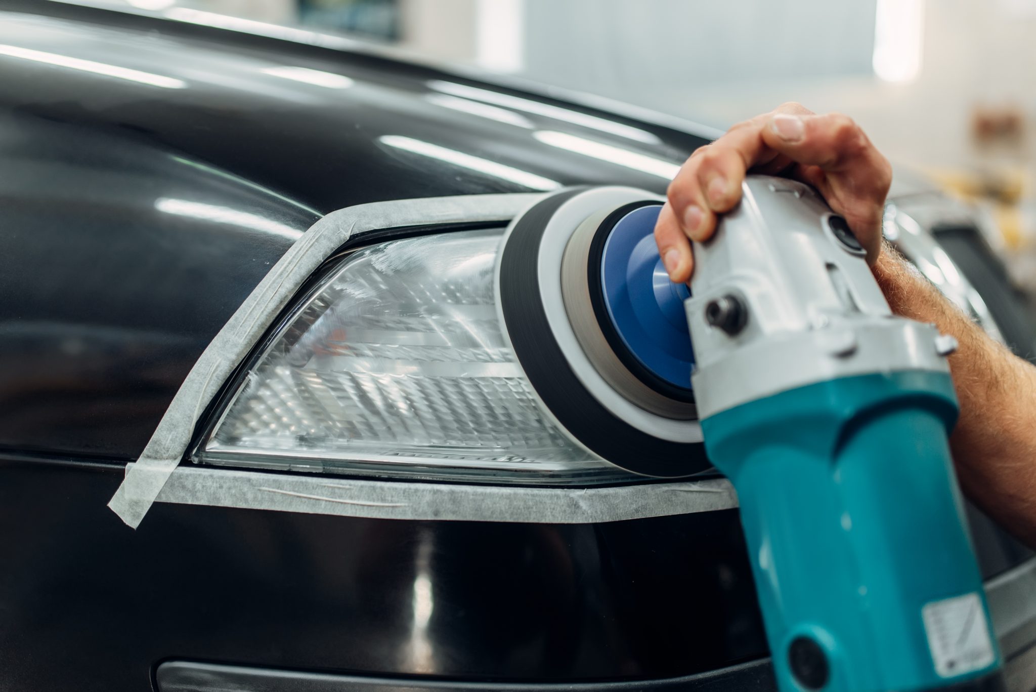 Technician polishing and restoring a vehicle headlight